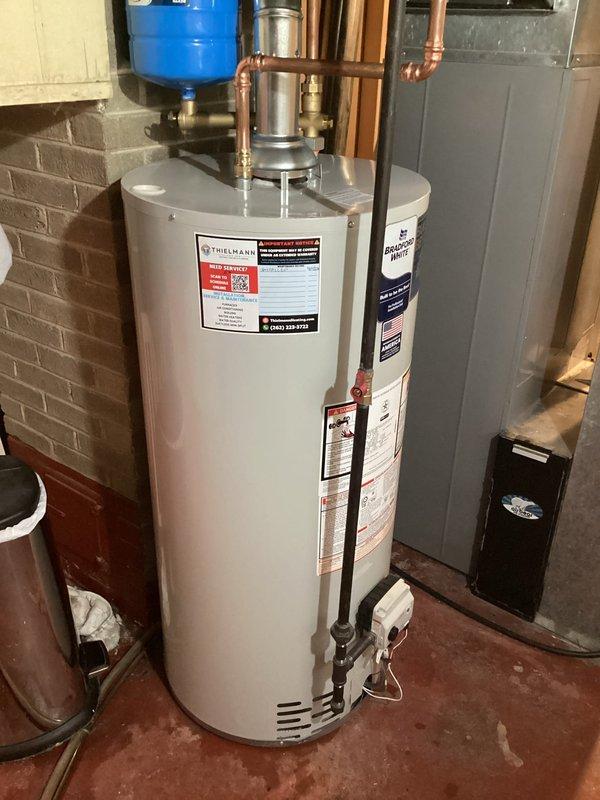 Installed 40-gallon Bradford White standard vent gas water heater in basement utility area. Unit was properly positioned, connected to existing copper supply lines with heat traps, installed pressure relief valve with discharge piping, and connected to gas supply with all necessary shut-off valves and controls verified operational.