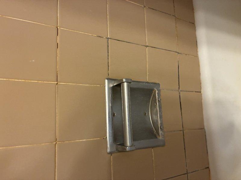 Responded to service call for water leak originating from shower and penetrating through wall into adjacent kitchen area. Performed diagnostic inspection of shower enclosure, examining tile work, grout lines, and built-in fixtures including recessed soap holder. Leak confirmed to occur only during shower operation, indicating probable failure of waterproofing membrane or compromised grout/caulk seals behind tile surface. Documented conditions with photographs showing tile wall configuration, mounted fixtures, and ceiling-to-wall transition areas for further assessment and repair recommendations.