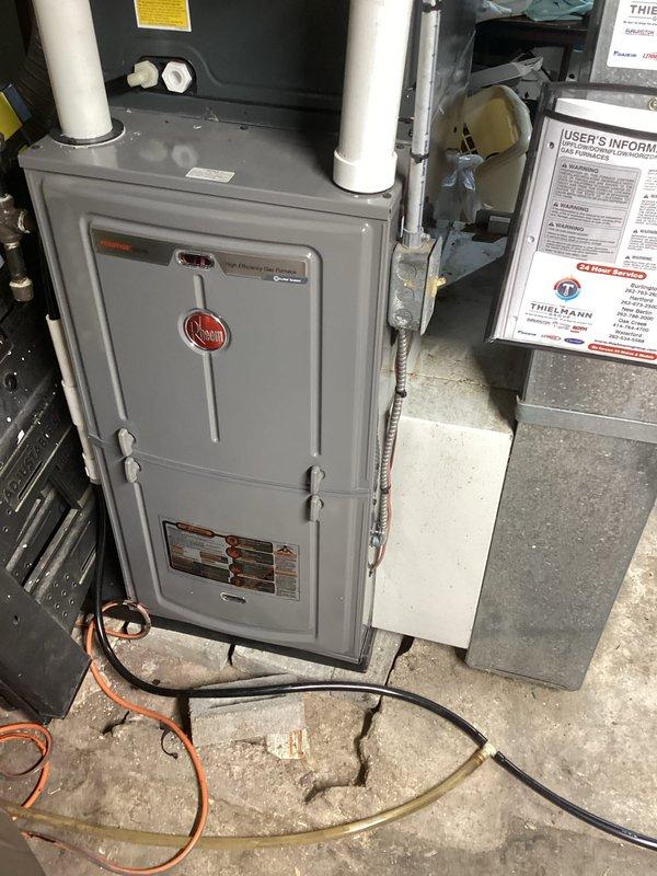 Completed comprehensive A/C tune-up on residential Rheem HVAC system located in basement mechanical room. Performed full system inspection including furnace cabinet, air handler, refrigerant lines, condensate drain system, and all associated components. Verified proper operation of white PVC exhaust and intake venting, checked copper refrigerant line connections, and confirmed all manufacturer labels and safety information remain legible and intact. System found to be in good working condition with organized component arrangement and clean installation.
