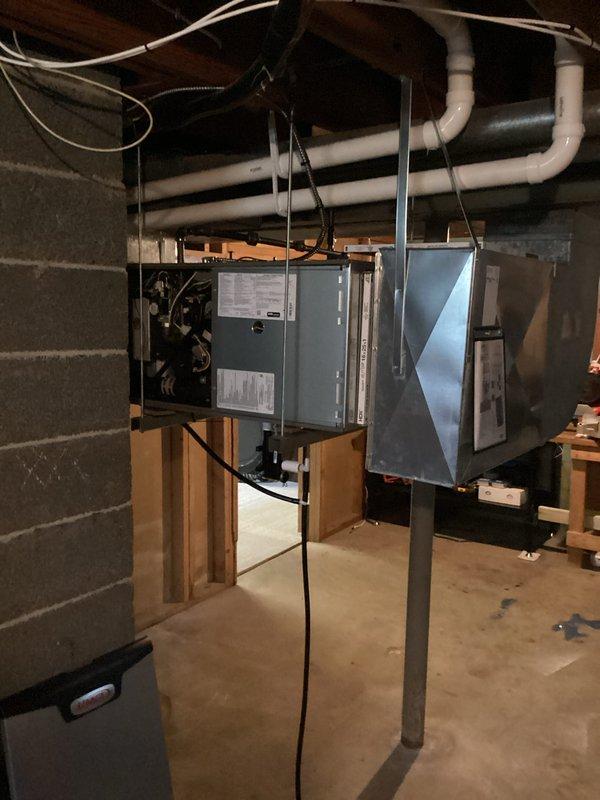 Completed horizontal furnace installation in basement utility space with equipment suspended from ceiling joists using metal straps and hangers. Unit was properly mounted to wooden joists with appropriate support hardware and clearances maintained per manufacturer specifications. Coordinated with licensed electrician for electrical connections and power supply installation. White PVC piping installed for condensate drainage and venting system routed horizontally across ceiling. All required permits obtained and installation performed in compliance with local building codes. Equipment positioned to allow adequate service access and proper airflow in the mechanical room setting.
