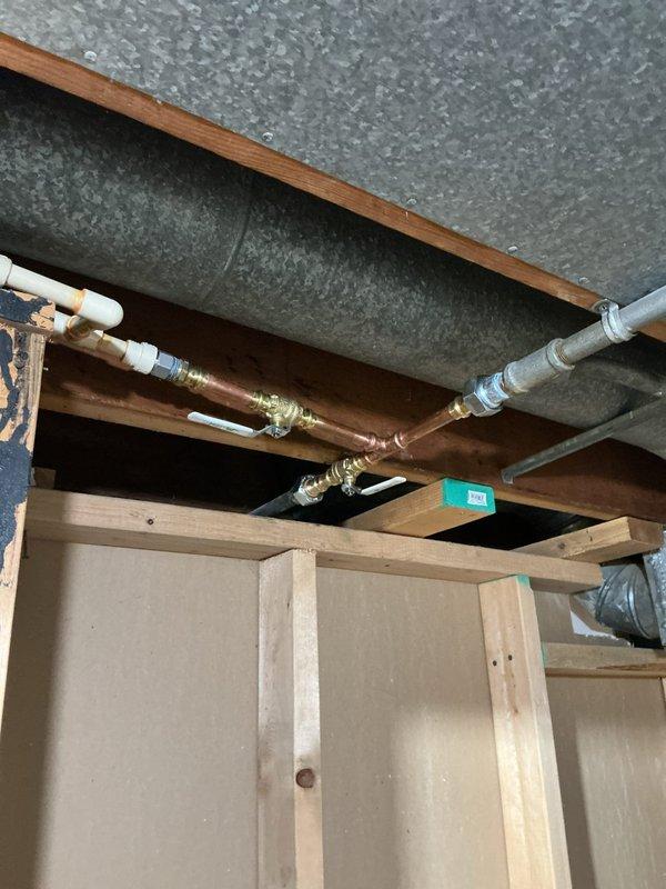 Coordinated with municipal water department to shut off water supply at the street main. Installed new shut-off valves before and after the water meter to establish functional main water control for the residence. Repiped water lines above the water heater using copper pipe and installed new dedicated shut-off valve for water heater isolation. Replaced supply valves for downstairs bathroom fixtures and reconnected to existing CPVC distribution lines. Replaced supply valves for upstairs bathroom fixtures with new quarter-turn ball valves. Cut access opening in ceiling to reach upstairs cold water line valve location and installed access panel for future maintenance. All valve replacements utilized quarter-turn ball valve technology for improved reliability and ease of operation. All new water supply piping installed with Type L copper pipe and brass fittings to ensure code compliance and system longevity.