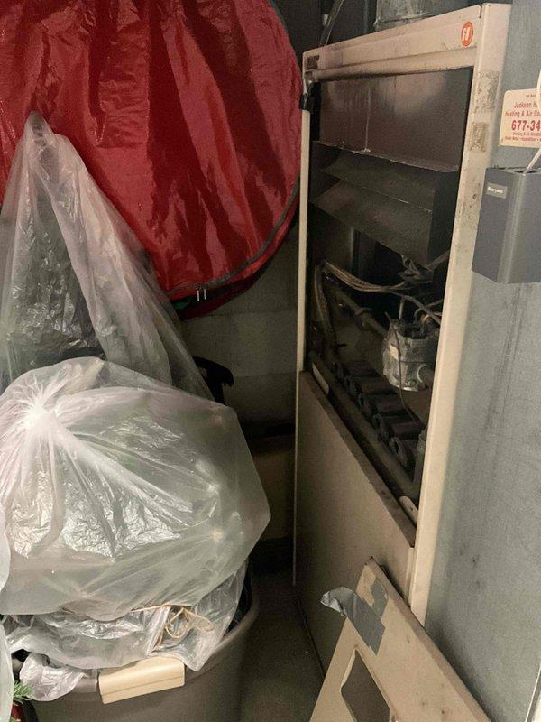 Conducted on-site evaluation of 50-year-old Lennox natural gas furnace located on first floor of raised ranch home. Unit currently operational but has reached end of expected service life. Assessed existing installation in rear utility area, documented equipment configuration and clearances. Photographed current furnace setup showing cabinet-style installation with mechanical components, venting, and gas connections. Provided comprehensive replacement estimate for new high-efficiency natural gas furnace system including removal of existing unit, installation of modern equipment, and necessary modifications to meet current code requirements.