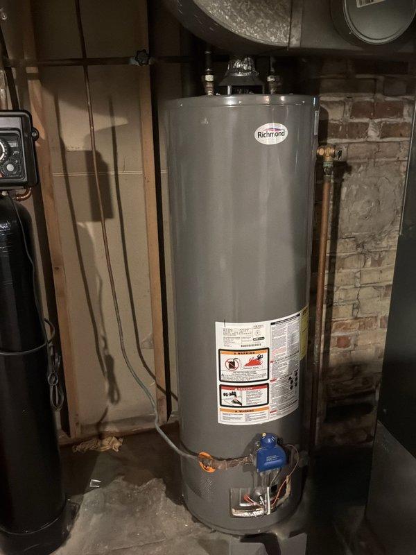 Responded to service call for non-operational water heater. Upon arrival, conducted visual inspection of Richmond brand residential water heater unit located in basement utility area. Assessed existing plumbing connections including copper supply lines, shut-off valve assembly with blue handle, and associated piping infrastructure. Documented current condition of unit, surrounding mechanical systems, and exposed ceiling structure where plumbing connections are routed. Provided estimate for water heater replacement or repair based on diagnostic findings and equipment condition assessment.