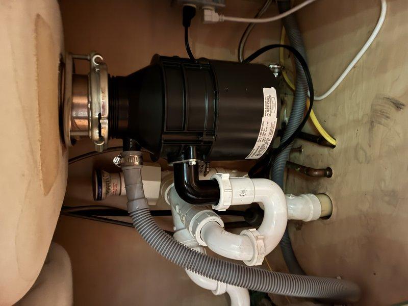 Installed new garbage disposal unit under kitchen sink. Connected disposal to existing drain assembly and PVC P-trap plumbing system. Secured all plumbing connections and verified proper drainage flow. Installation completed successfully with disposal unit operational and tested for functionality.