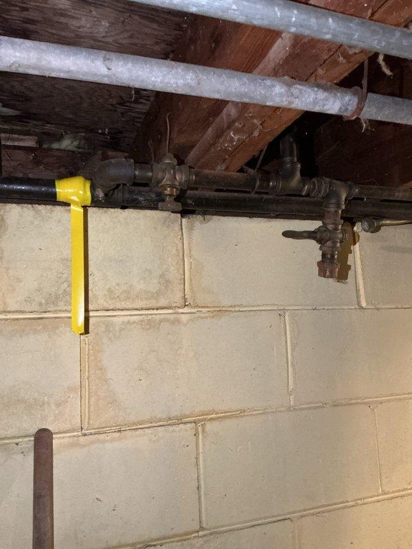 Responded to emergency call for water gushing from pipe near sump pump in basement crawl space. Upon inspection, located burst pipe in the vicinity of the sump pump system and performed necessary repairs to stop active water flow. Assessed existing galvanized and black iron piping throughout the basement area, noting aged infrastructure with visible corrosion on metal components and fittings. Discussed with property owner the condition of gas lines that had previously experienced leaks and provided recommendations for permanent pipe replacement to address ongoing concerns with deteriorating piping system. Documented current state of mechanical systems including exposed piping, ductwork, and valve assemblies for future reference and planning of comprehensive pipe replacement project.