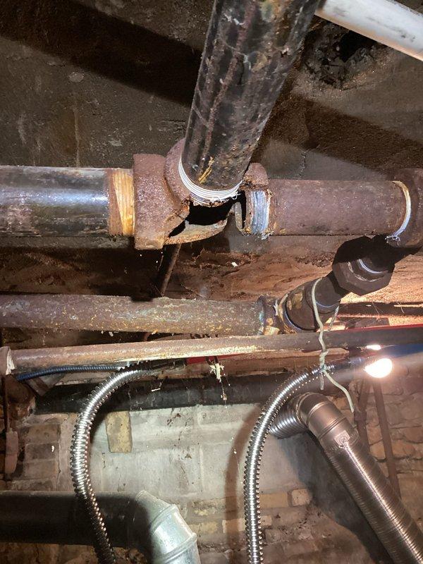 Responded to service call for older, larger boiler with significant water leakage throughout the system. Upon arrival, performed diagnostic inspection and discovered severely corroded pipe joint with complete separation at connection point, causing active water leak. The deteriorated piping infrastructure showed extensive rust, oxidation, and age-related wear across multiple components. Documented the compromised plumbing connections and assessed overall system condition. Additionally observed water damage to interior ceiling and walls, indicating the leak had been ongoing. Provided assessment findings and discussed repair versus replacement options given the extent of corrosion and age of the equipment.