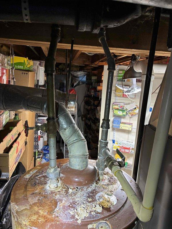 Responded to service call for water heater with water pooling from top of unit. Upon arrival, performed visual inspection and documented existing conditions. Assessment revealed significant corrosion and rust on water heater drain pan, with visible mineral deposits and scale buildup indicating active leaking from upper connections. Inspected surrounding plumbing connections, ductwork, and utility area infrastructure. Photographed corroded drain pan, deteriorated piping components, and overall installation conditions. Prepared estimate for complete water heater replacement based on observed failure conditions and safety concerns related to ongoing water discharge from top of unit.