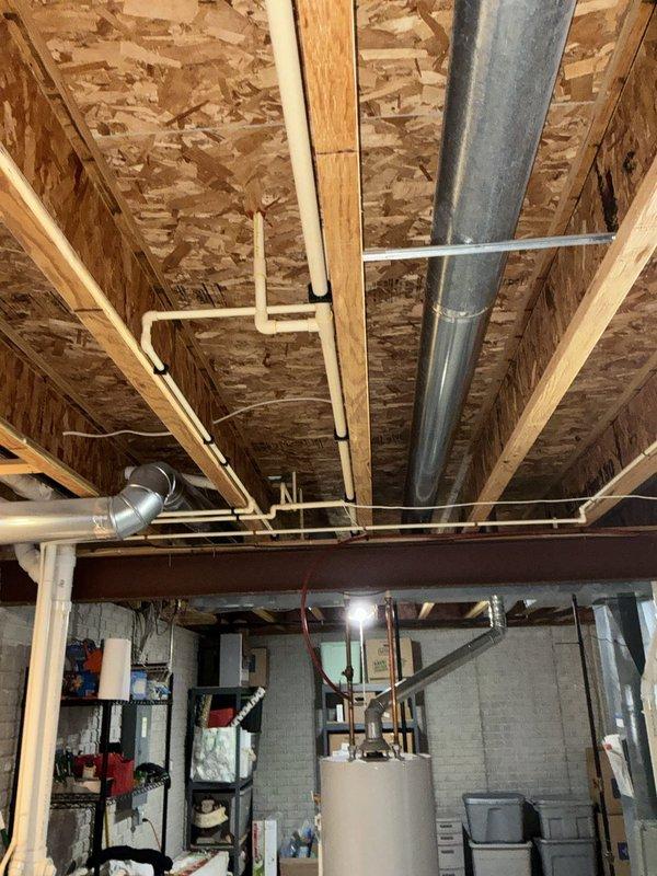 Conducted site assessment for gas line extension from basement to second floor. Documented existing gas infrastructure including current 1/2" flex lines serving dryer and stove, along with 3/4" supply line running through basement ceiling joists. Evaluated routing path through floor framing system and identified access points for vertical run to second floor. Photographed existing utility layout including HVAC ductwork, structural supports, and water heater location to determine optimal pipe routing while maintaining clearances from other building systems.