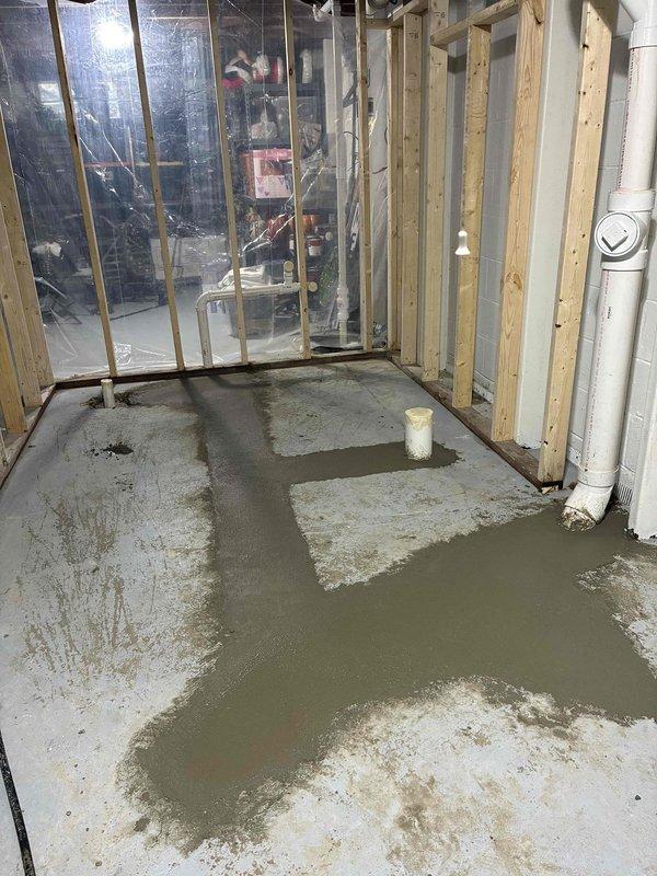 Completed rough-in plumbing installation for new full bathroom addition in unfinished basement. Installed complete drainage system including PVC waste lines routed through ceiling joists and vertical drain stacks mounted to concrete block walls. Ran water supply lines utilizing both PVC and copper piping to accommodate future fixture locations. Poured and leveled concrete floor sections in cross-pattern configuration to establish proper drainage slopes and prepare substrate for fixture installation. Coordinated plumbing rough-in with existing HVAC ductwork and electrical systems in ceiling space to ensure proper clearances and code compliance.