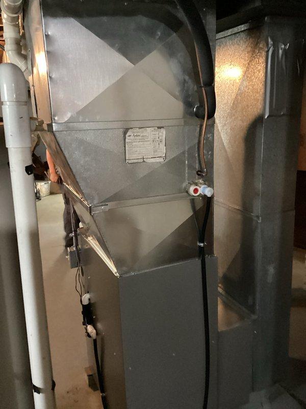 Completed full furnace installation in basement mechanical room with all required permits obtained. New gray metal furnace unit installed on concrete pad with proper clearances, including connection of black flexible ducts, refrigerant lines with service ports, and white PVC venting system secured to floor joists with appropriate hangers. Licensed electrician completed all electrical connections and wiring in accordance with local codes. System tested and verified operational upon completion.