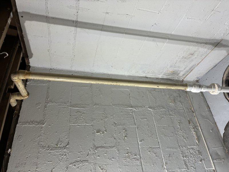 Responded to service call for sump pump issues at residential property. Upon arrival, conducted thorough inspection of basement utility area and sump pump system. Examined discharge piping system, including horizontal PVC drainage lines and mounting hardware secured to concrete block walls. Inspected ceiling-mounted piping infrastructure and verified proper slope and support of discharge lines. Evaluated ventilation opening and associated ductwork in utility space for proper clearance and functionality. Assessed overall condition of plumbing connections, joints, and elbow fittings throughout the sump pump discharge system. Documented existing conditions with photographs for service records. System components showed normal wear consistent with age of installation. All piping connections and mounting brackets were secure and functioning as designed.