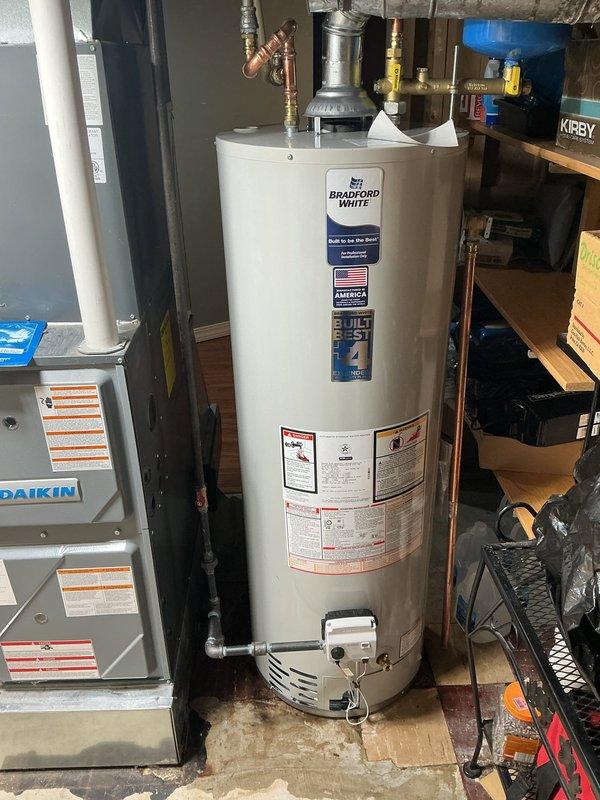 Installed a 40-gallon Bradford White standard vent water heater in basement utility area. Connected copper water supply lines, installed temperature and pressure relief valve with proper brass fittings, and attached metal flue pipe for exhaust venting. Gas control valve and burner assembly were properly configured, and all plumbing connections were secured to manufacturer specifications. Warranty documentation was tagged and placed as requested, and installation was completed without requiring permit per management direction.