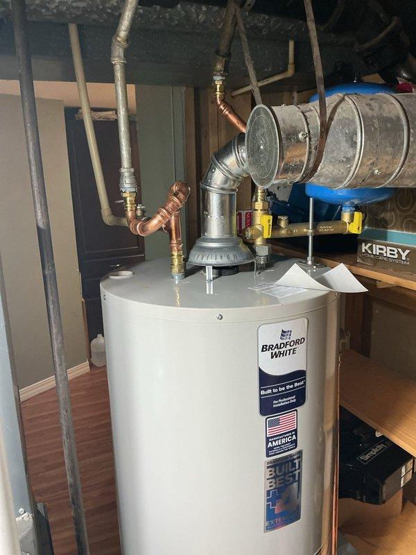 Installed a 40-gallon Bradford White standard vent water heater in basement utility area. Connected copper water supply lines, installed temperature and pressure relief valve with proper brass fittings, and attached metal flue pipe for exhaust venting. Gas control valve and burner assembly were properly configured, and all plumbing connections were secured to manufacturer specifications. Warranty documentation was tagged and placed as requested, and installation was completed without requiring permit per management direction.