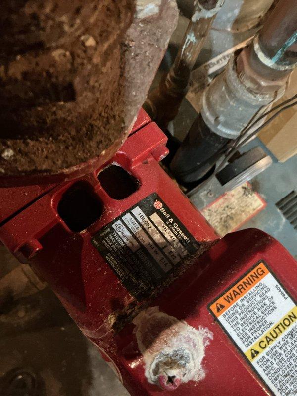 Responded to service call for boiler system serving 8-unit apartment complex experiencing banging noise, which had been shut down by occupants. Accessed basement mechanical room and performed diagnostic inspection of boiler and associated circulator pumps. Identified circulator pump #2 as source of noise complaint. Inspected pump assembly, motor mounts, piping connections, and system components for mechanical failure, cavitation, or air entrainment issues. Documented equipment condition with photographs showing red-painted circulator pump with visible wear, mounting configuration, and connected piping. Evaluated system operation, pressure conditions, and potential causes of banging including water hammer, loose mounting hardware, or impeller damage within pump assembly.