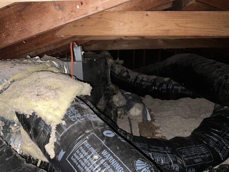 Completed estimate for attic-mounted air handler replacement serving residential HVAC system. Evaluated existing functional but aging unit located in attic space with exposed wooden framework, assessed current ductwork configuration including black flexible ducts, and inspected outdoor Carrier condenser unit mounted on concrete pad against exterior brick wall. Provided replacement recommendations and pricing options for complete air handler system upgrade.