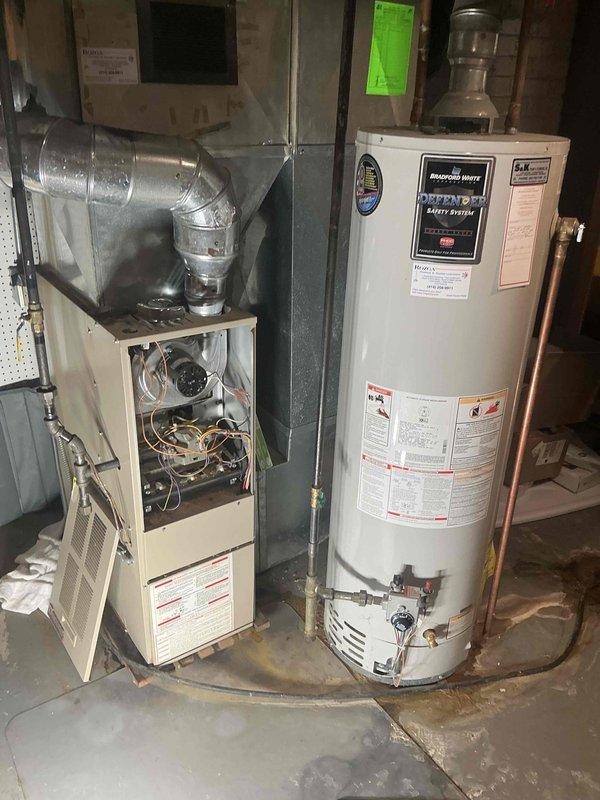 Responded to emergency service call for furnace and air conditioning system evaluation. Upon arrival, conducted thorough assessment of existing HVAC equipment in basement mechanical room. Inspected gas furnace with access panel open to evaluate internal components, burners, and overall system condition. Examined air conditioning system and associated ductwork. Documented equipment age, condition, and operational status through detailed photography. Noted water heater proximity and basement environmental conditions including floor staining. Provided comprehensive replacement estimate for both heating and cooling systems based on equipment assessment and customer needs.