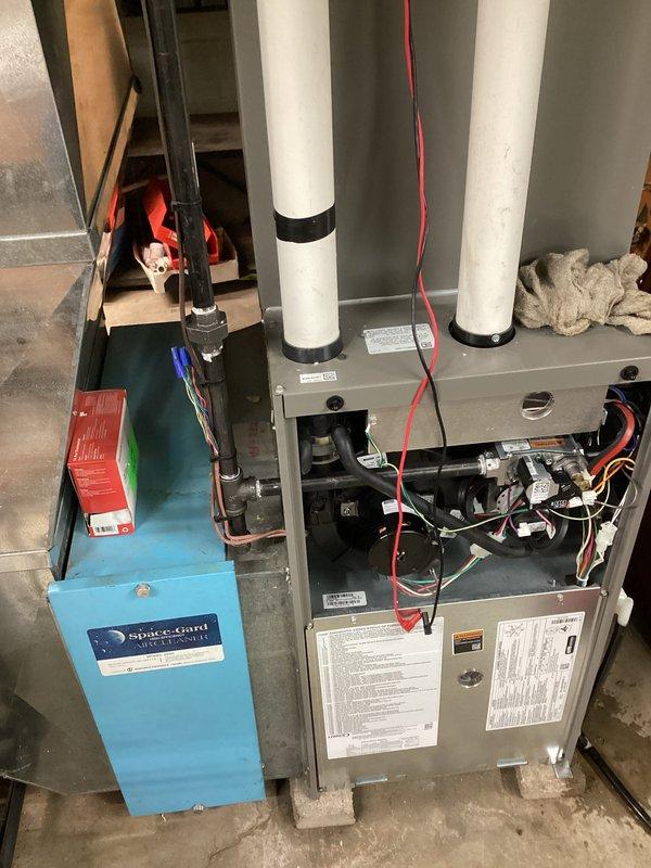 Completed furnace and air conditioning tune-ups on dual HVAC system. Inspected Space-Gard air filtration unit, furnace blower assembly, electrical connections, and venting components. Noted significant contamination on evaporator coil fins with dark staining in lower sections and visible cracks in drain pan indicating age-related deterioration that may require future attention.