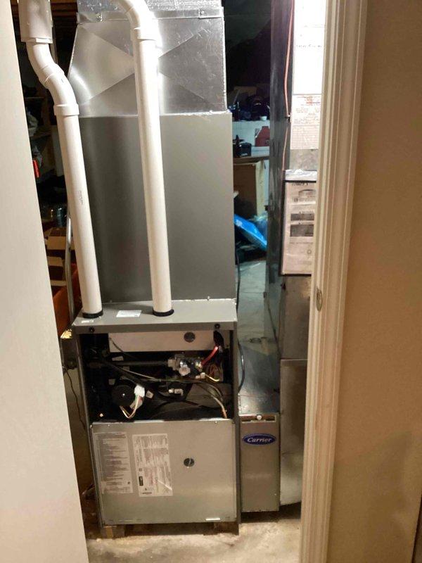 Completed full HVAC system installation including Carrier brand furnace and air conditioning unit. Installed furnace with proper venting using white PVC piping for condensate drain and combustion air intake/exhaust. Routed refrigerant lines (suction and liquid lines) and electrical connections from outdoor condensing unit to indoor air handler through exterior ground-level pathway. Secured all refrigerant lines with proper insulation and protection. Connected ductwork to plenum assembly and verified all mechanical and electrical connections at furnace control board. Work performed with required permits and licensed electrician coordination for electrical service connections. System installed in interior utility closet with outdoor condenser placement adjacent to building exterior. All components properly positioned and secured for optimal operation and future service accessibility.
