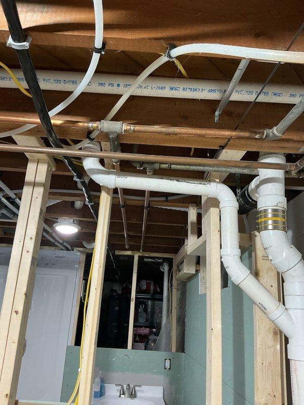 Completed plumbing inspection of exposed basement ceiling infrastructure per customer concern regarding needle valve and clamp installation. Examined copper supply lines, PVC drainage system, and associated mechanical fittings throughout unfinished utility space. Documented existing plumbing configuration including copper piping connections to PVC components via metal fittings, verified proper support and securing methods for all visible lines. Assessed needle valve and clamp assembly for structural integrity and code compliance, confirmed adequate clearance from ceiling joists and electrical conduit. Provided photographic documentation of current installation and recommended next steps for addressing customer concerns about blocking and ceiling finishing work.