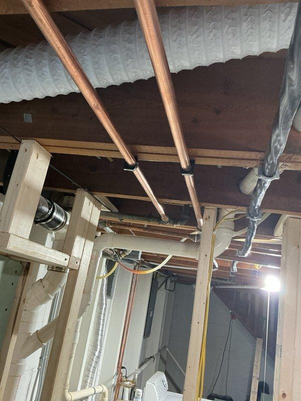 Completed plumbing inspection of exposed basement ceiling infrastructure per customer concern regarding needle valve and clamp installation. Examined copper supply lines, PVC drainage system, and associated mechanical fittings throughout unfinished utility space. Documented existing plumbing configuration including copper piping connections to PVC components via metal fittings, verified proper support and securing methods for all visible lines. Assessed needle valve and clamp assembly for structural integrity and code compliance, confirmed adequate clearance from ceiling joists and electrical conduit. Provided photographic documentation of current installation and recommended next steps for addressing customer concerns about blocking and ceiling finishing work.