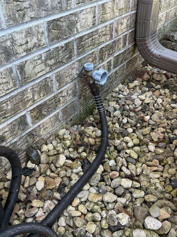 Conducted pre-purchase plumbing assessment of residential property identifying exterior hose bib installation with black flexible supply line connected to PVC shutoff valve mounted on brick foundation, and inspected crawlspace drainage system including vertical drain stack with proper P-trap configuration beneath subfloor. Documented existing plumbing infrastructure conditions for prospective homeowner to determine necessary repairs and upgrades prior to closing.