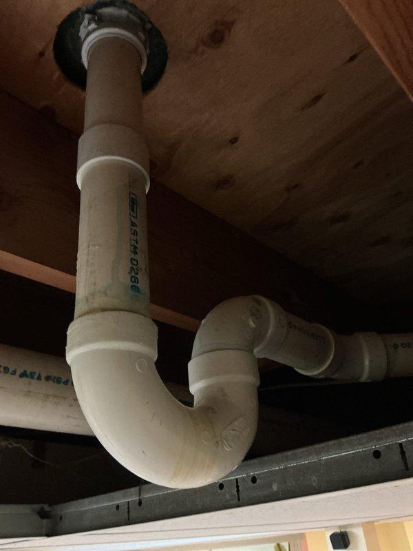 Conducted pre-purchase plumbing assessment of residential property identifying exterior hose bib installation with black flexible supply line connected to PVC shutoff valve mounted on brick foundation, and inspected crawlspace drainage system including vertical drain stack with proper P-trap configuration beneath subfloor. Documented existing plumbing infrastructure conditions for prospective homeowner to determine necessary repairs and upgrades prior to closing.