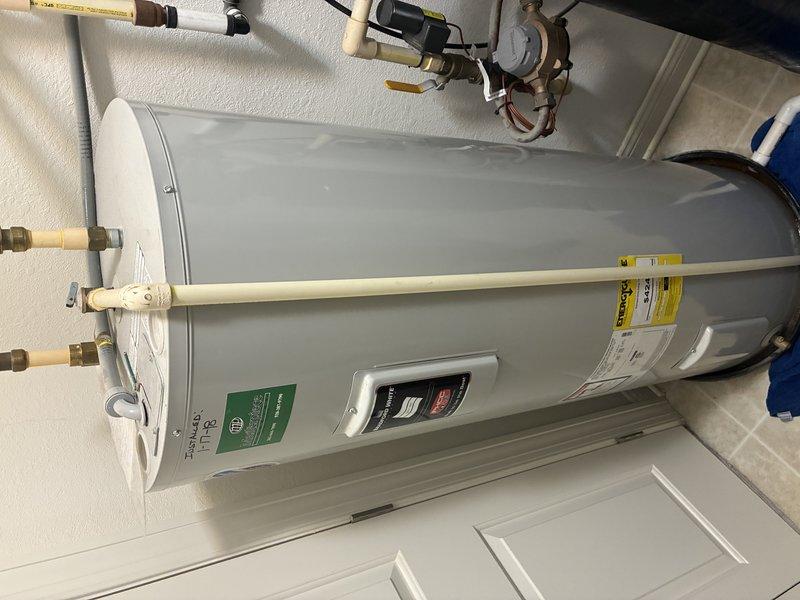 Responded to service call for leaking gas tanked water heater. Upon inspection, identified a Rheem 50-gallon electric water heater (Model RE35035-3) with visible moisture at connection points. Examined all copper pipe connections, brass fittings, and pressure relief valve assembly at top of unit. Documented equipment condition with photos showing installation details, specification labels, and connection configuration. Contacted property owner with diagnostic findings and repair recommendations for tenant-occupied property.