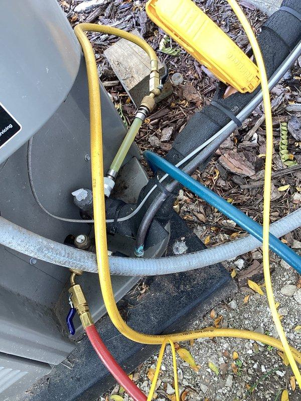Responded to no cooling call and performed diagnostic evaluation of residential air conditioning system. Connected manifold gauges and vacuum pump to service ports to check refrigerant charge and system pressures. System found to be low on refrigerant, indicating potential leak or undercharge condition requiring further assessment and refrigerant recovery/recharge procedures.