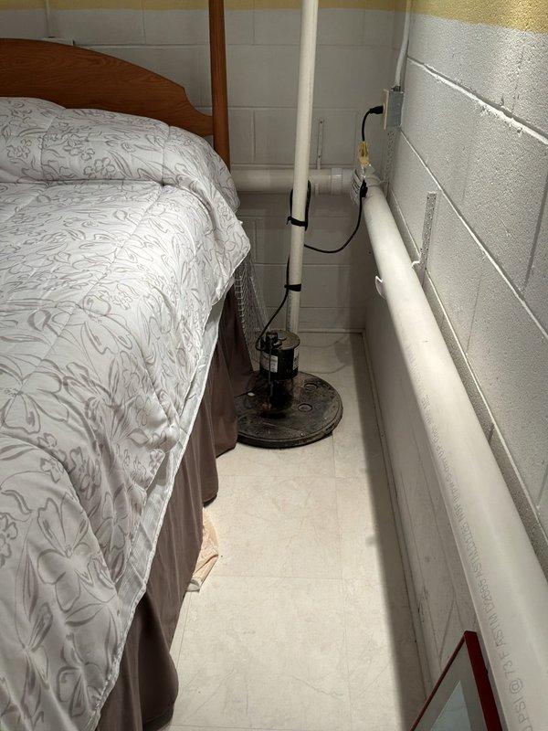Completed comprehensive whole home plumbing inspection of residential property. Evaluated all accessible plumbing systems including water supply lines, drainage systems, sump pump operation in basement utility area, and pressure tank functionality. Inspected white PVC drainage piping, mounting brackets, and sump pump installation with electrical connections in lower level, confirming proper operation and clearances. Assessed pressure tank system including gauge readings, connections, black supply piping, flexible tubing, and associated electrical control panel. All components photographed and documented for service records, with systems found to be operational at time of inspection.