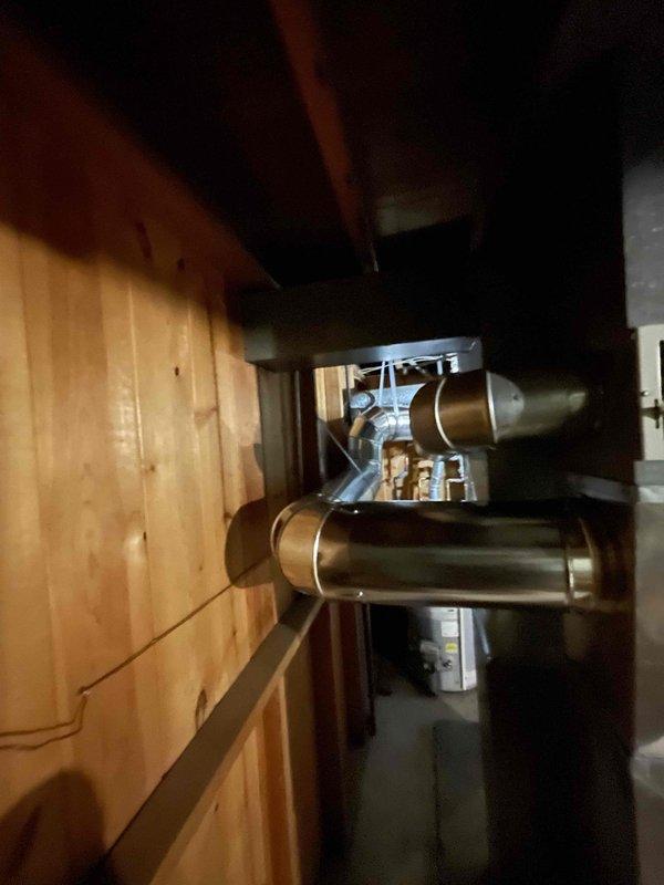 Completed HVAC ductwork installation in basement utility area. Installed metallic rigid ductwork with proper mounting brackets and ceiling supports, including elbow transitions for optimal airflow routing. Connected flexible and rigid ductwork to water heater exhaust system with appropriate venting materials and reflective insulation wrapping to meet code requirements for safe operation.