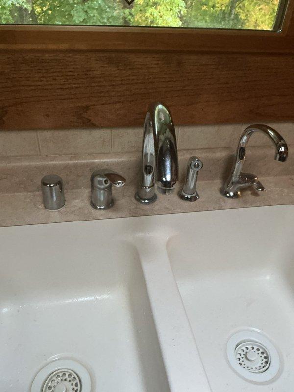 Replaced gooseneck single-handle kitchen faucet with chrome finish fixtures, including side sprayer attachment and soap dispenser. Installed new supply lines and P-trap assemblies for double-basin sink configuration. Customer also reported water softener and iron filter system cycling nightly between 9:59-11:00 PM, which appears to be operating on its programmed regeneration schedule.