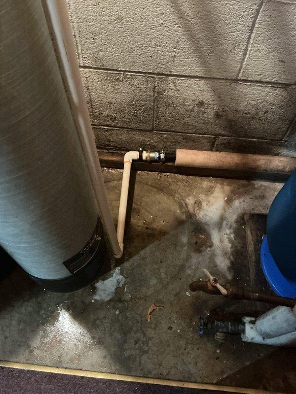 Completed installation of Spitfire brand water softener system in residential basement utility area. Unit was properly positioned, connected to existing copper water supply lines, and equipped with control head for automated operation. All plumbing connections were secured and tested for proper function. System was left operational with installation documentation provided on-site.