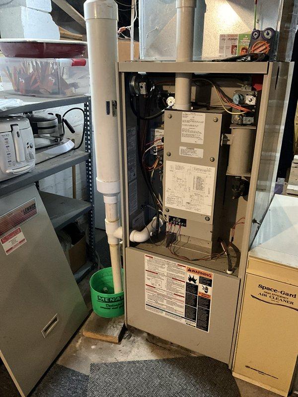 Completed comprehensive HVAC system evaluation for furnace replacement estimate in residential mechanical room. Assessed existing beige furnace unit with open access panel, documented internal components including control board and wiring configuration, examined white PVC condensate drain and vent piping, and evaluated overall system condition. Photographed equipment specifications, warning labels, and surrounding infrastructure including ductwork and mechanical connections to provide accurate replacement recommendations and equipment sizing requirements.