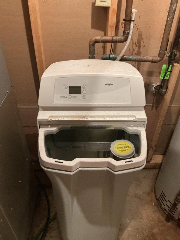Performed diagnostic service on Whirlpool water softener experiencing complete drainage failure. Inspected unit installation, control panel functionality, and associated plumbing connections including copper supply and drain lines. Documented equipment condition and utility room configuration with water heater proximity for service records.