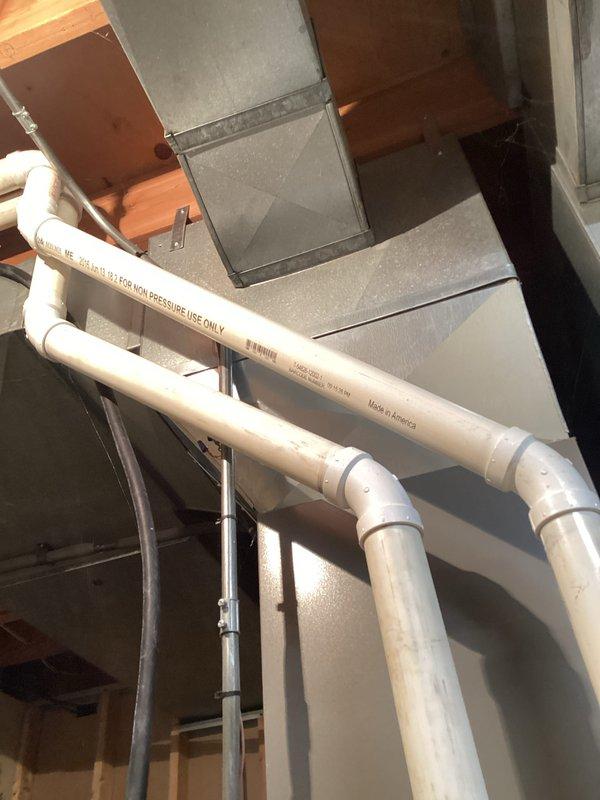 Completed preventive maintenance tune-up on HVAC system. Inspected ductwork and drainage components in mechanical space, confirmed proper installation and condition of PVC condensate lines and metal ductwork with all seams and joints secure. Verified system operating temperatures using infrared thermometer, recording 116.6°F discharge temperature indicating normal heat operation.