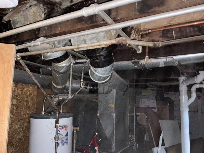 Conducted on-site assessment of residential plumbing system requiring partial pipe replacement in basement utility area. Evaluated existing infrastructure where walls were already opened, revealing mix of copper, PVC, and gray piping systems running throughout exposed ceiling joists. Identified remaining sections of piping requiring replacement to bring system up to code, while noting that majority of piping had already been updated. Documented current configuration including water heater connections, drain lines, and supply lines to provide comprehensive estimate for completing remaining pipe replacement work.