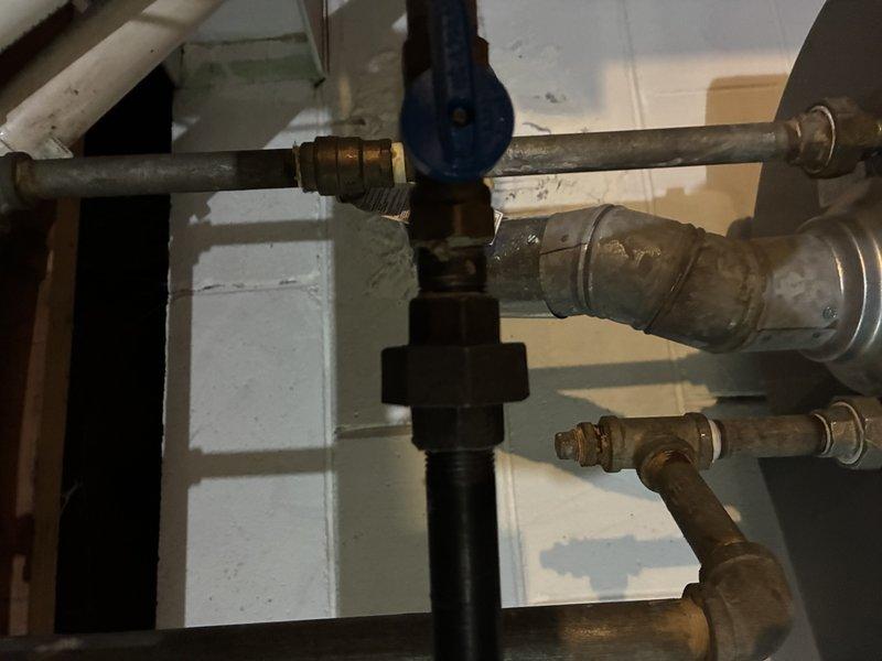 Conducted comprehensive piping estimate for hot water distribution system and gas stove installation. Assessed existing plumbing infrastructure including aged copper supply lines, brass fittings, and gas piping connections with blue shutoff valve. Documented current condition of threaded black iron gas pipe with buildup near water heater, photographed multiple pipe junctions showing patina and discoloration, and evaluated compatibility of existing system for proposed gas appliance hookup.