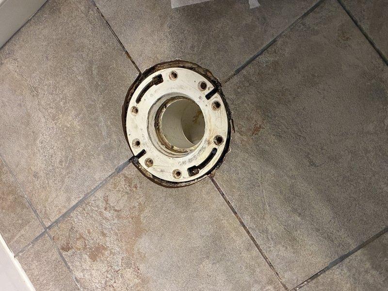 Completed toilet flange replacement at residential bathroom. Removed deteriorated flange showing significant rust staining and corrosion around mounting bolt holes. Installed new flange, ensuring proper seal and secure mounting to existing tile floor. Toilet reinstalled and tested for proper operation and leak-free performance.