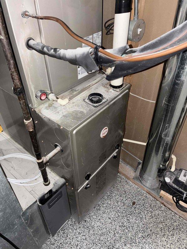 Responded to no heat call with reported odor and non-functioning air conditioning system. Upon arrival, inspected residential furnace unit in utility closet and found system operational with ambient temperature reading of 72.9°F. Performed visual inspection of furnace cabinet, refrigerant lines, condensate drain, and ductwork connections. No active fault conditions detected at time of service call. Unit appeared to have accumulated normal dust and debris on exterior surfaces. All visible components including copper refrigerant lines with insulation, PVC condensate piping, and electrical connections showed no signs of immediate failure or safety concerns.