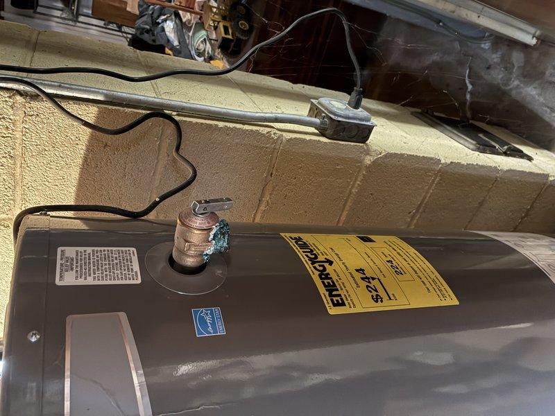 Diagnosed and identified a leaking temperature and pressure relief valve on a Rheem 40-gallon power vent water heater model PV12-2. Upon inspection, the T&P valve showed visible corrosion and deterioration at the copper pipe connection, with heavy oxidation present on the fitting. The valve was actively leaking, creating a potential safety hazard and water damage risk. Documented the condition of the unit and the corroded T&P valve assembly with photographic evidence showing the extent of the deterioration and the water heater's location in the utility space.