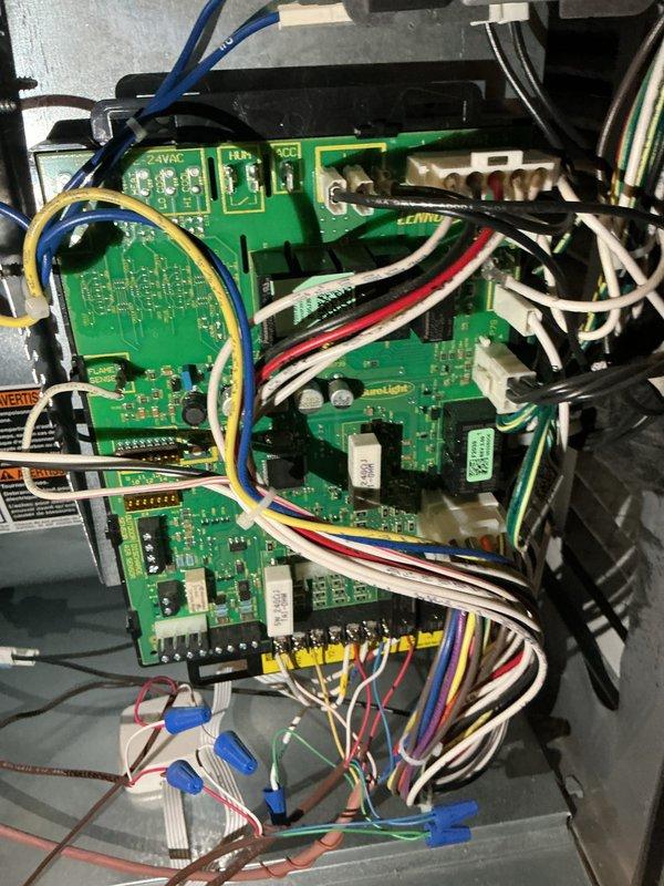 Completed comprehensive tune-up service on HVAC system, including inspection of control board wiring and electronic components within the unit housing. Documented existing wiring configuration showing multiple circuit boards with various colored wire connections; inspected condensate drain line assembly with 90-degree elbow fitting to ensure proper drainage function.