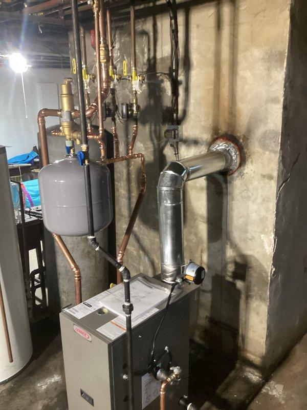 Completed full boiler replacement in basement mechanical room with all required permits and licensed electrician coordination. Installed new boiler unit with complete copper piping distribution system, expansion tank, water filtration system, gas valving with safety shutoffs, and proper venting through foundation wall with sealed penetration. All connections, fittings, ball valves, and control wiring installed to manufacturer specifications and local code requirements, with system tested and operational upon completion.