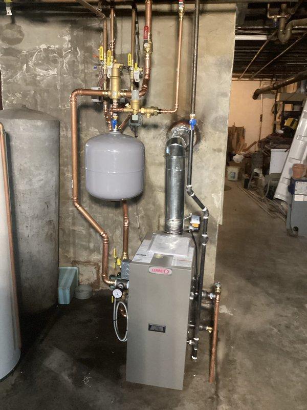 Completed full boiler replacement in basement mechanical room with all required permits and licensed electrician coordination. Installed new boiler unit with complete copper piping distribution system, expansion tank, water filtration system, gas valving with safety shutoffs, and proper venting through foundation wall with sealed penetration. All connections, fittings, ball valves, and control wiring installed to manufacturer specifications and local code requirements, with system tested and operational upon completion.