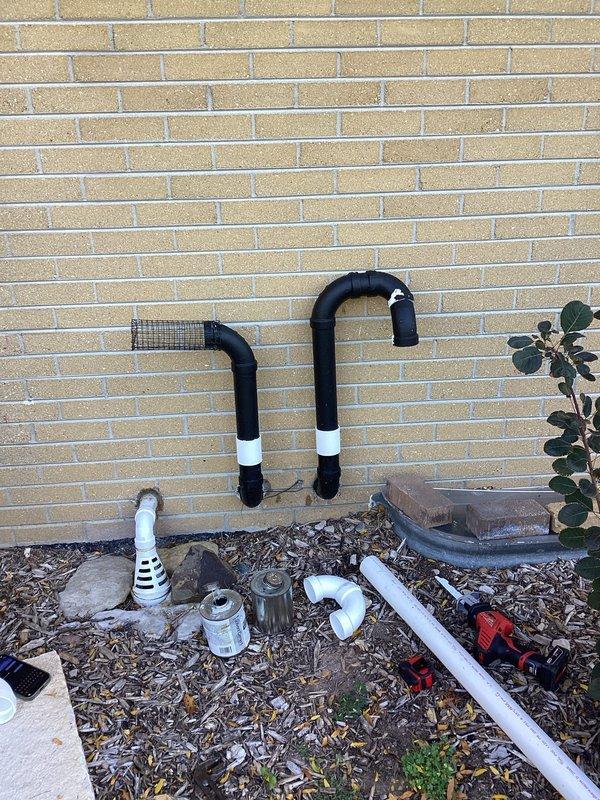 Completed warranty termination rework on exterior condensate drain system. Reinstalled PVC drain line assembly with proper 90-degree elbow configuration and secured vertical discharge pipe to exterior wall. Repositioned drain pan with stabilizing blocks at base to ensure proper condensate collection and verified all connections for leak-free operation.