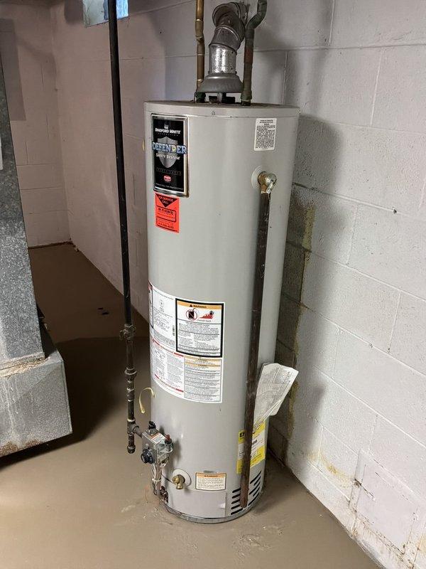 Responded to service call for leaking water heater. Upon arrival, performed diagnostic inspection and confirmed active water leak from tanked water heater unit. Assessed condition of equipment and surrounding area, documenting water damage on basement floor near base of unit. Evaluated water heater for potential repair versus replacement, noting age and extent of leak. Photographed existing plumbing configuration including water softener system, brine tank, copper supply lines, and venting assembly for service records.