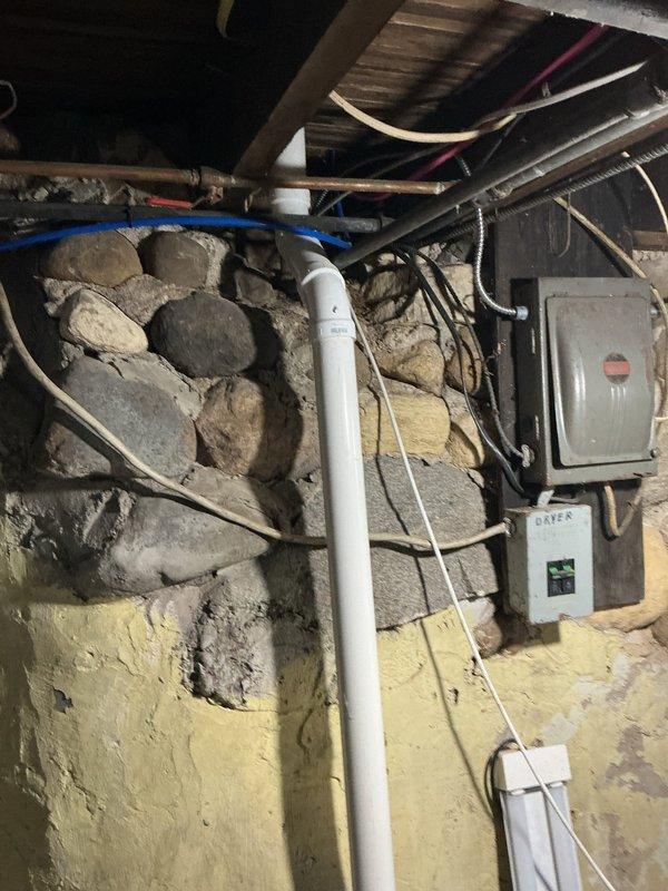 Responded to service call for non-flushing toilet and general plumbing assessment. Inspected bathroom fixtures including toilet and vanity plumbing connections, as well as basement utility area containing main plumbing lines, PVC drainage system, and associated infrastructure mounted along stone foundation wall. Diagnosed toilet flushing mechanism failure and evaluated condition of visible supply lines, drain pipes, and aged plumbing components throughout accessible areas. Documented existing plumbing configuration with photographic evidence for repair recommendations and potential replacement considerations.