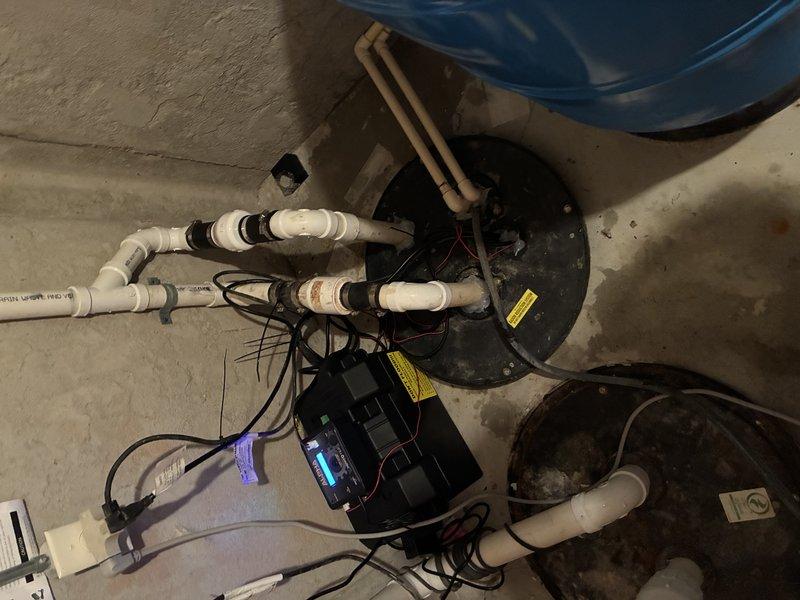 Completed installation of Alpha-1 sump pump replacement system in basement utility area. Installed new sump pump unit with yellow float switch assembly in existing concrete basin, connected discharge piping using white PVC with proper joints and fittings, and configured electrical controls and power connections to ensure proper pump operation and automatic water level management.