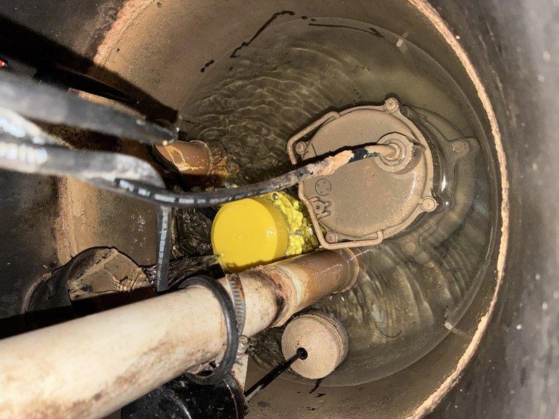 Completed installation of Alpha-1 sump pump replacement system in basement utility area. Installed new sump pump unit with yellow float switch assembly in existing concrete basin, connected discharge piping using white PVC with proper joints and fittings, and configured electrical controls and power connections to ensure proper pump operation and automatic water level management.