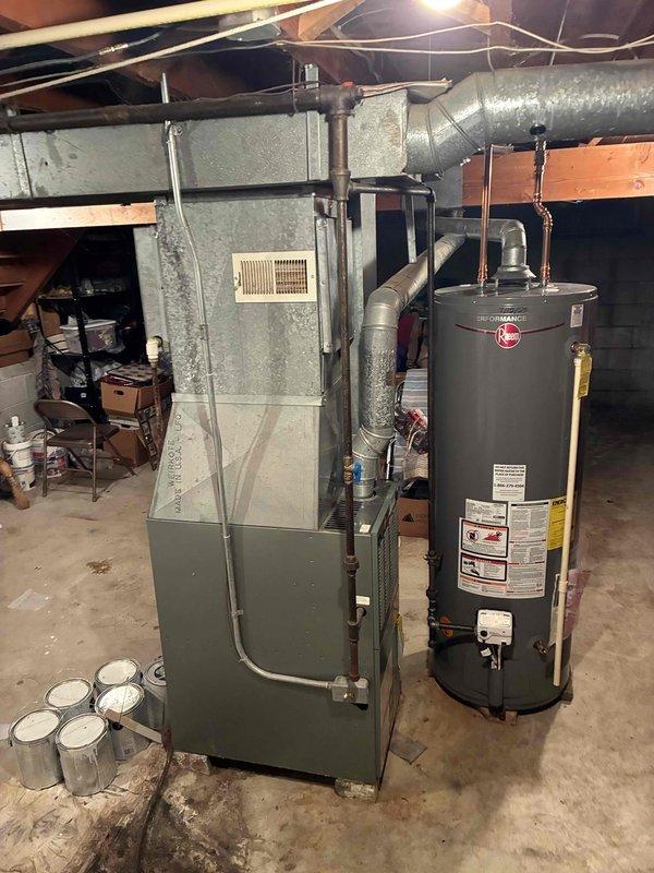 Conducted estimate for replacement of 28+ year old natural gas furnace and air conditioning system located in basement area of tri-level residence. Existing olive-green cabinet-style furnace unit with metal ductwork connections showed age-related wear consistent with equipment at end of service life. Documented current HVAC equipment configuration, ductwork layout, and installation access points for replacement planning. Photographed existing furnace installation, water heater proximity, basement utility room conditions, and floor drain location to assess equipment removal and new system installation requirements.