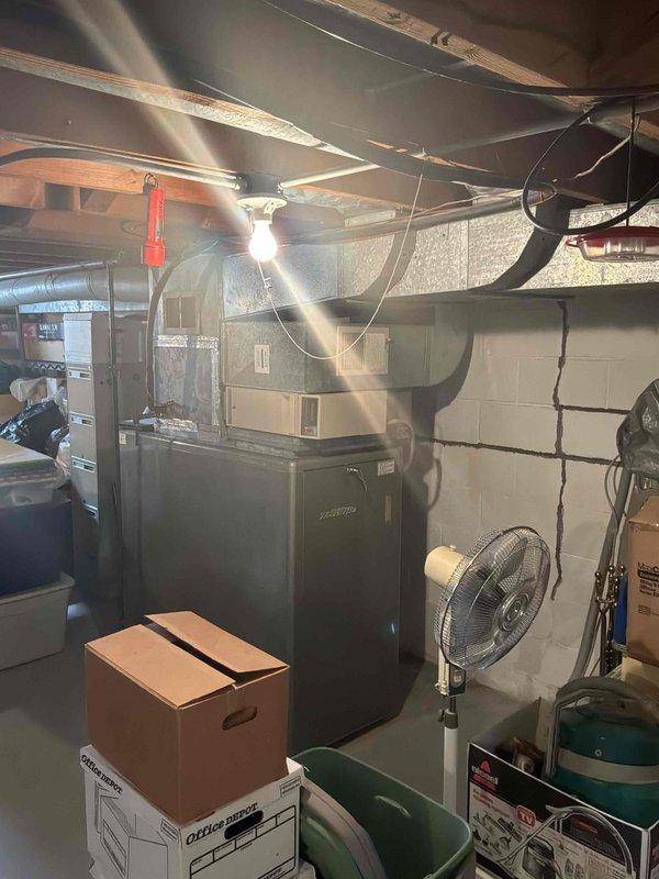 Performed an on-site evaluation for a full system replacement of an aging natural gas furnace located in the basement and a non-operational outdoor air conditioning condenser that has been inoperative for over a year. Inspected the existing furnace, plenum, and ductwork configuration, and documented the condenser, electrical disconnect, and surrounding site conditions, noting heavy vegetation growth around the unit and cracking in the basement block wall. Provided a replacement estimate for a new furnace and AC system.
